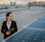 A business woman looking out to a city landscape on a rooftop with solar panels