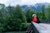 Young woman backpacker hikes across bridge in the forest