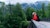 Young woman backpacker hikes across bridge in the forest